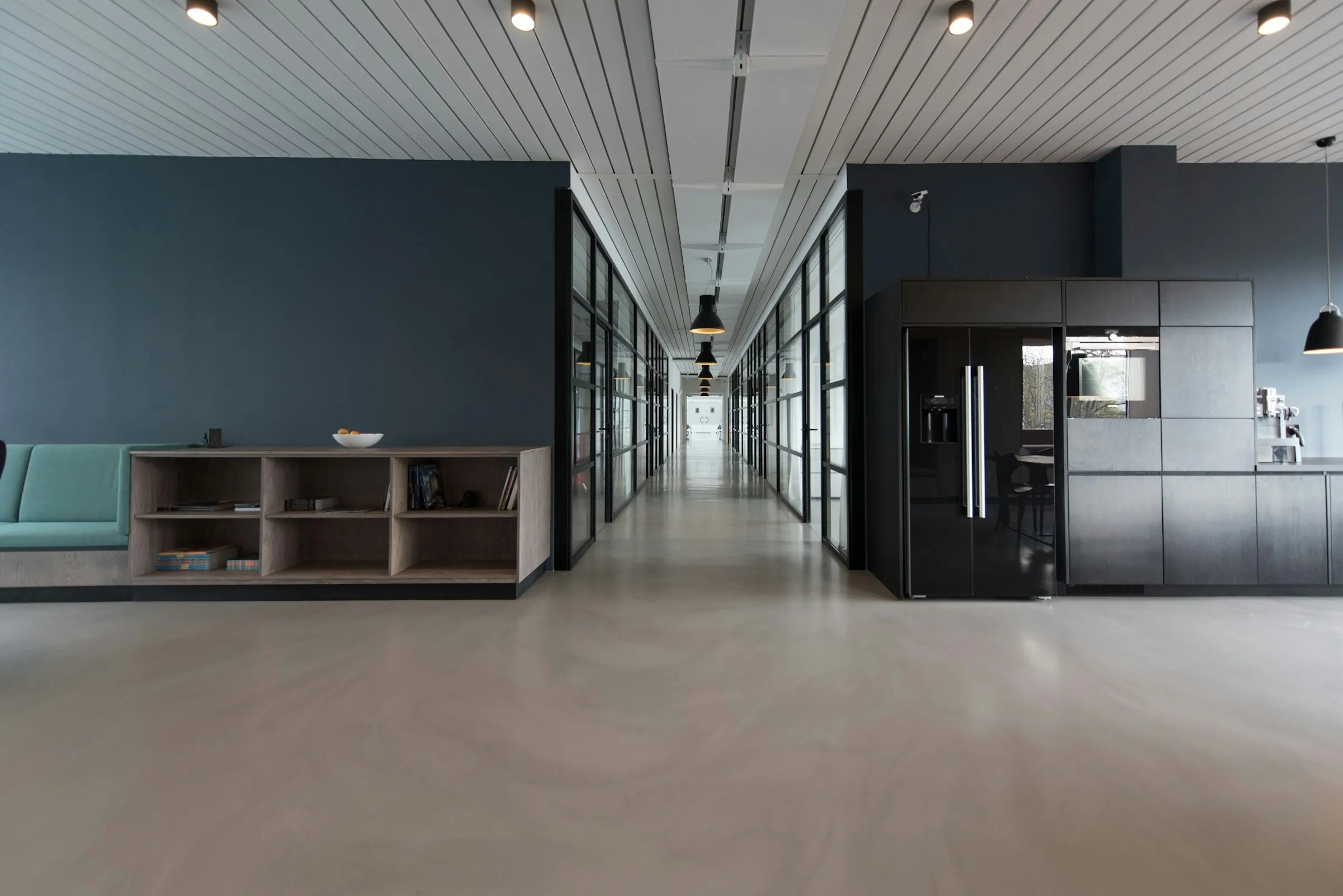 Modern open-plan office with a clean polished floor and glass-walled corridor